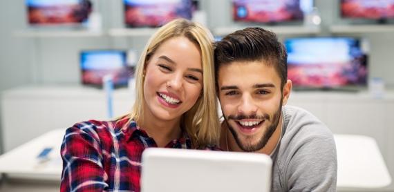 Customers looking at a device in a shop for electronics